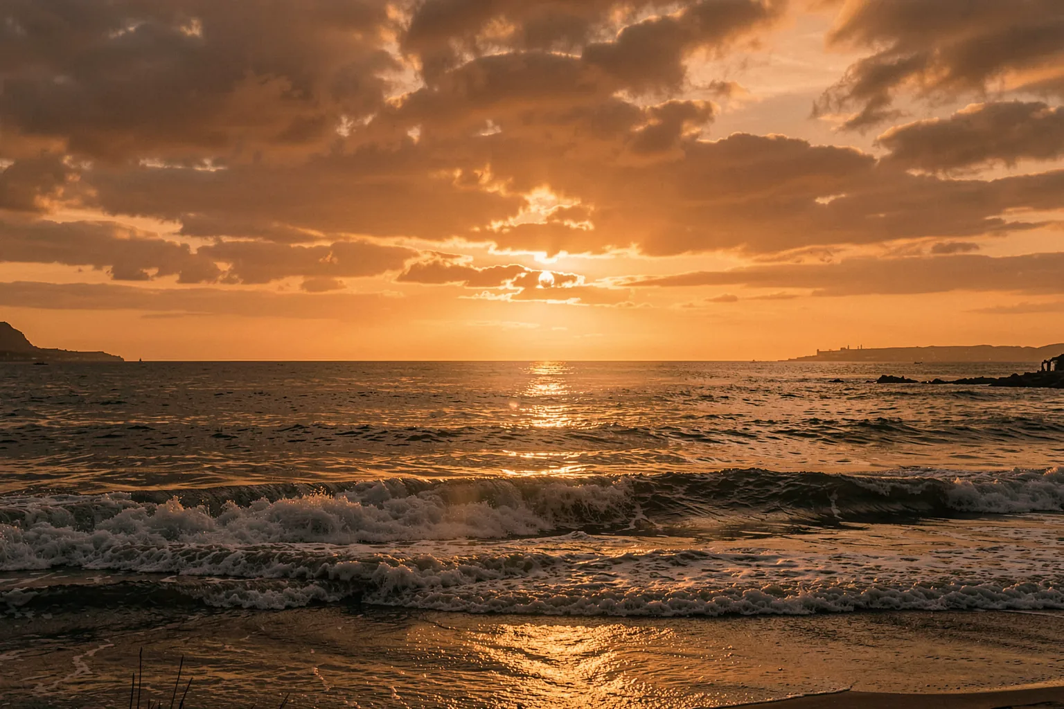 Golden Ocean Sunset. An orange sun sets over a dark ocean, with glowing light reflected across the water beneath clouded skies.