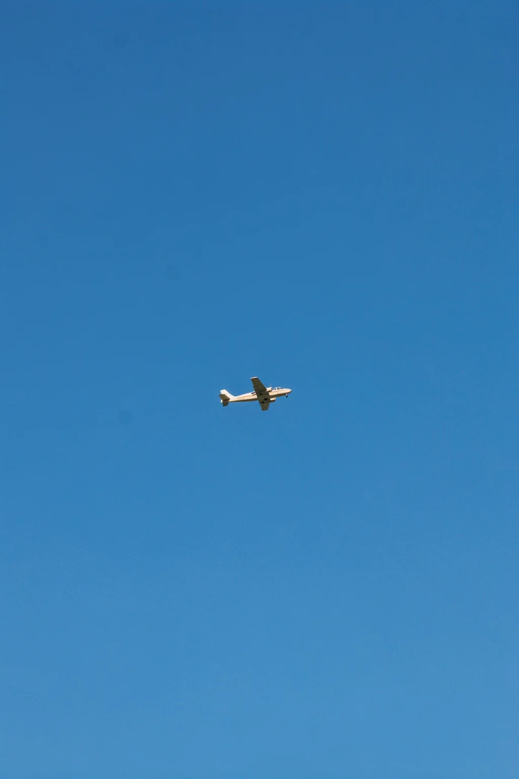 No stress. A small white airplane crosses an open, cloudless blue sky.