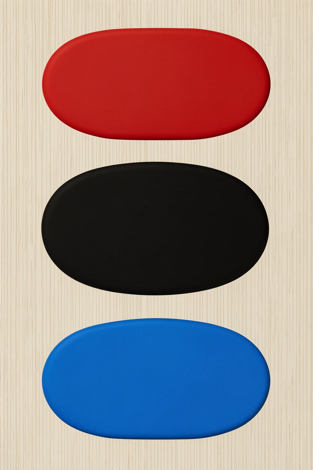 Stacked Color Blocks. Three textured pill-shaped blocks in red, black, and blue are stacked vertically on a cream field.
