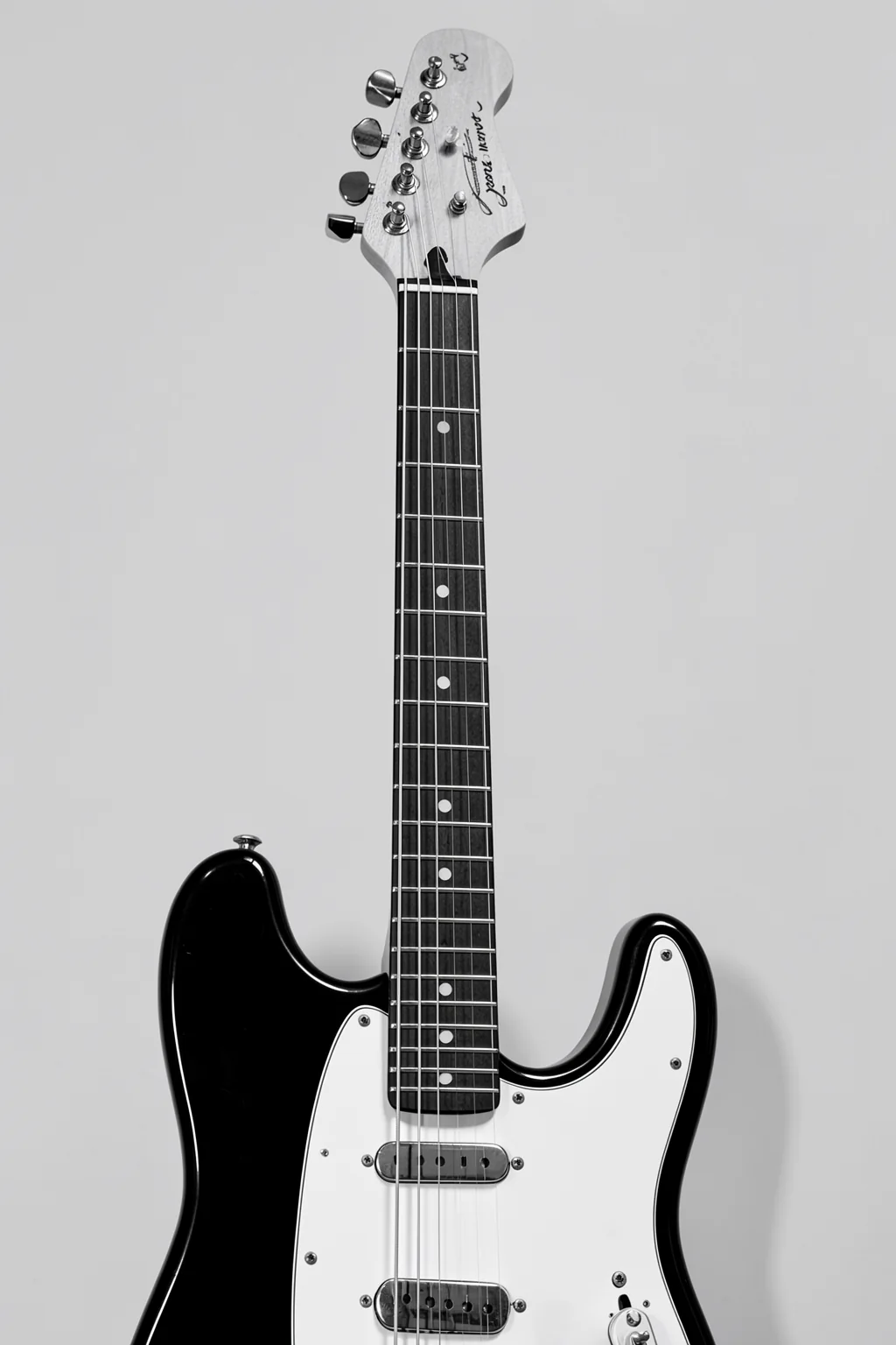 Monochrome Electric Guitar. A black-and-white electric guitar is shown upright against a plain light gray background.
