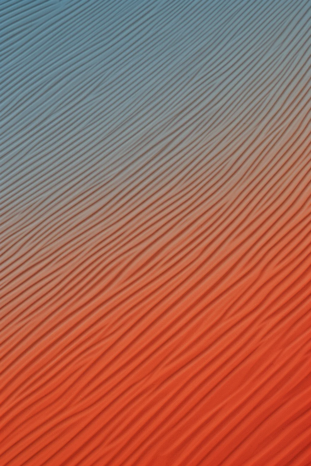 Colorful Desert Ripples. Fine diagonal ridges run across a surface that shifts from muted blue-gray to warm coral.