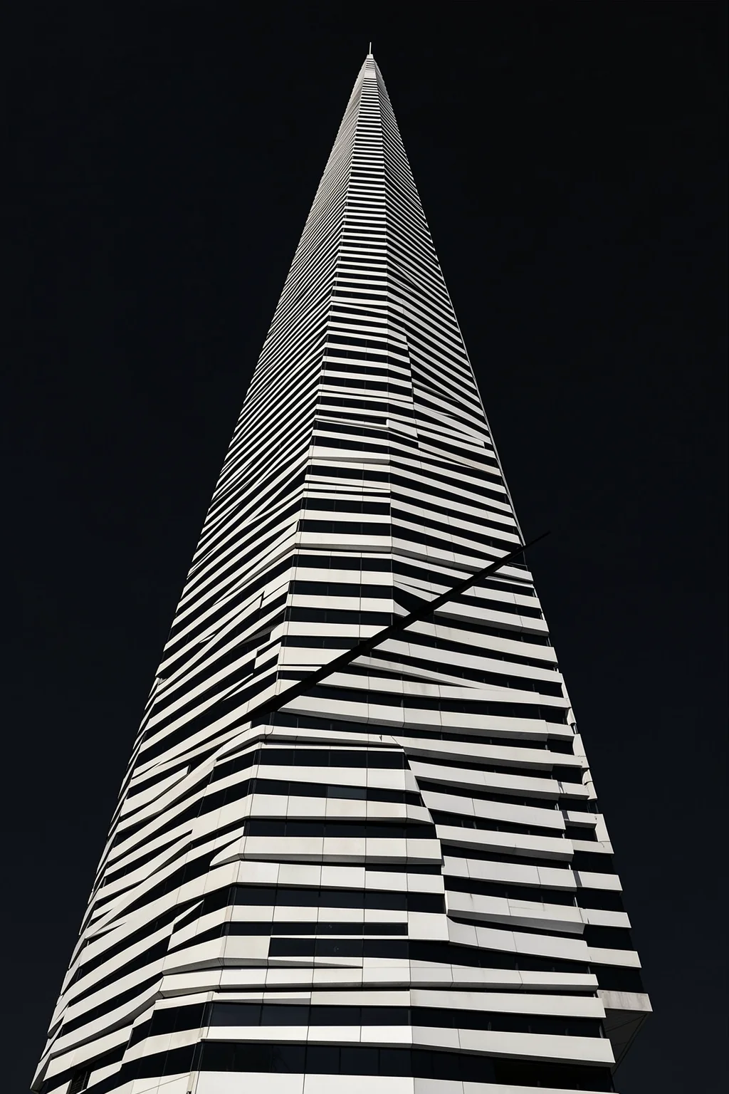 Modern Architectural Curves. A tall modern tower with alternating black-and-white horizontal bands rises into a dark sky, viewed from below.