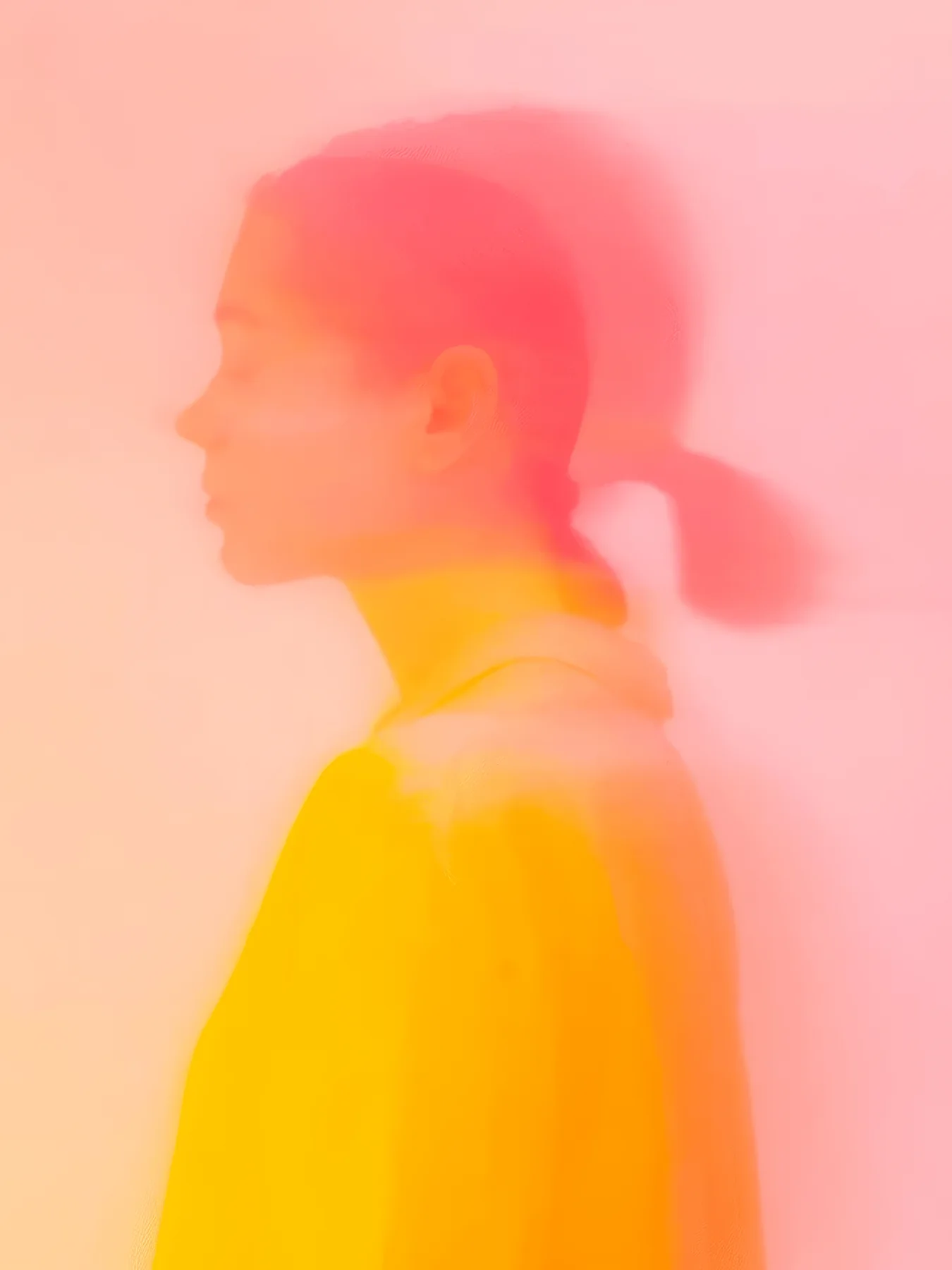 Onlly poster, Woman in Golden Light: A softly blurred profile glows in coral, pink and yellow tones.