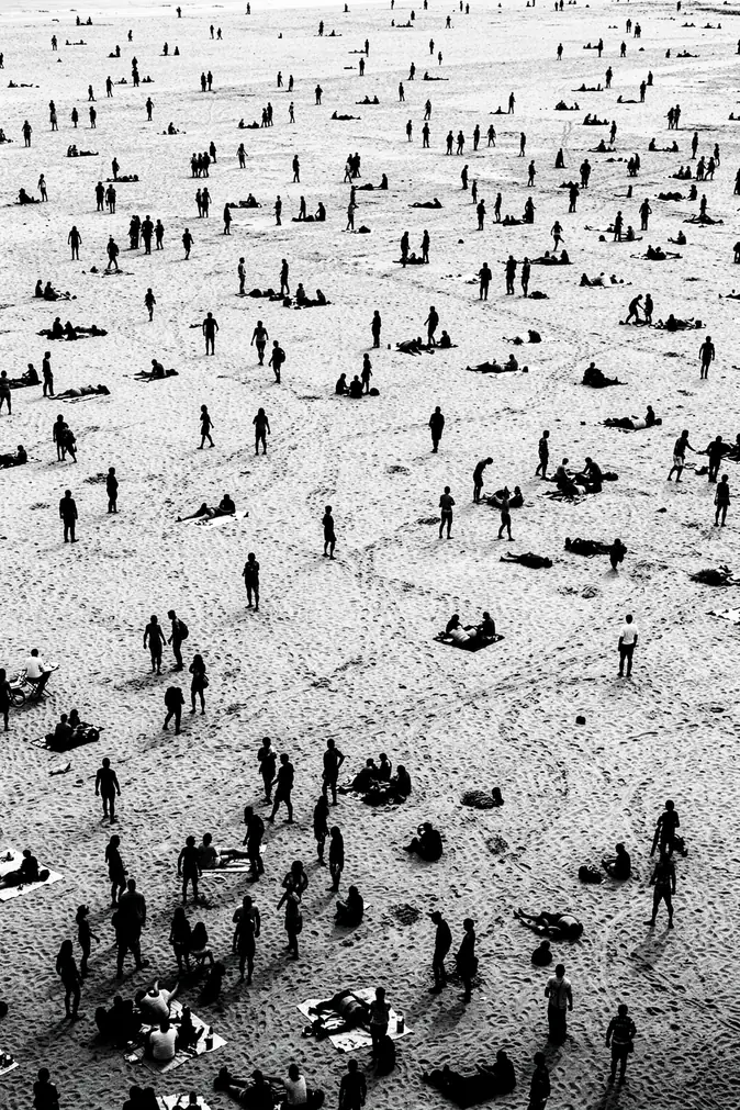 Beach Silhouettes. A black-and-white aerial view shows many tiny people scattered across a broad pale beach.