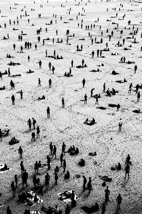 Beach Silhouettes. A black-and-white aerial view shows many tiny people scattered across a broad pale beach.