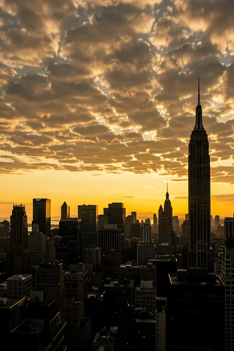 Dramatic New York City Skyline. The New York skyline, including the Empire State Building, appears in silhouette beneath dramatic golden sunset clouds.
