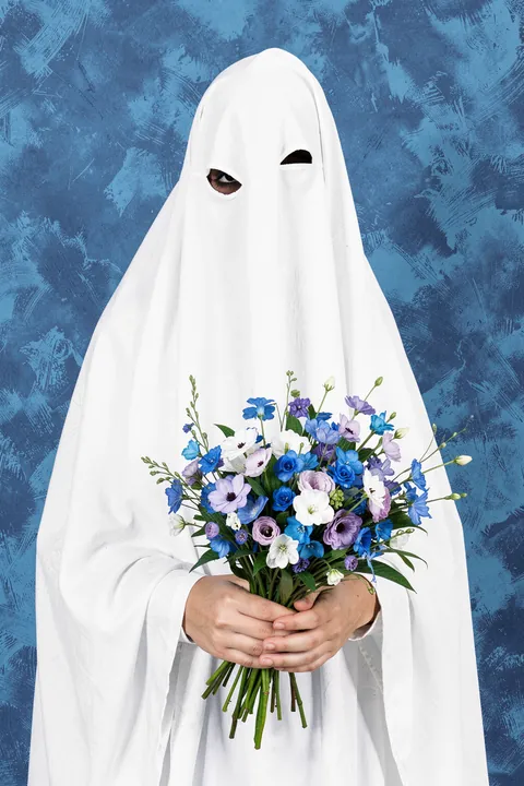 Ghost. A figure draped in a white sheet holds a bouquet of blue, white, and lavender flowers against a textured blue wall.