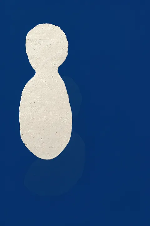 Abstract Blue Form. A textured white, rounded vertical shape with a faint blue-gray shadow stands on a deep-blue field.