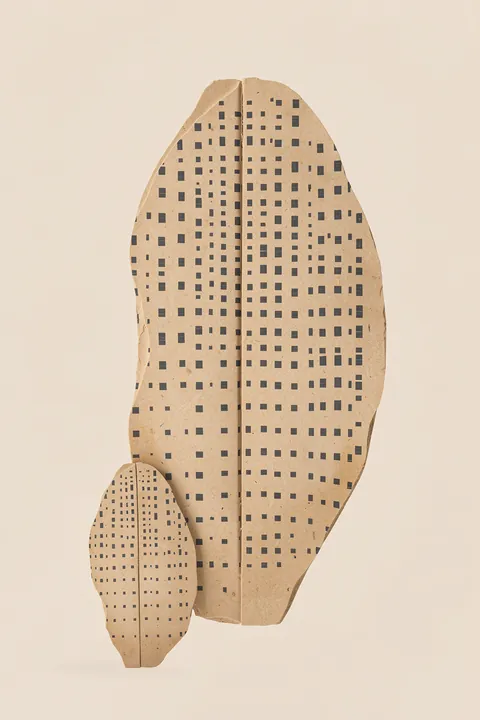 Organic Patterned Shapes in grey green on beige.. Two upright tan leaf-like shapes covered in small dark squares overlap against a pale beige background.