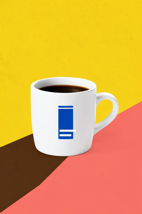 Tazza. A white coffee cup with a blue geometric mark sits on a yellow field above coral and dark brown diagonal shapes.