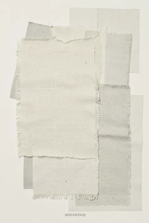 Linen Layers. Overlapping off-white rectangles with visible woven texture and frayed edges sit on a pale background, with small lettering below.