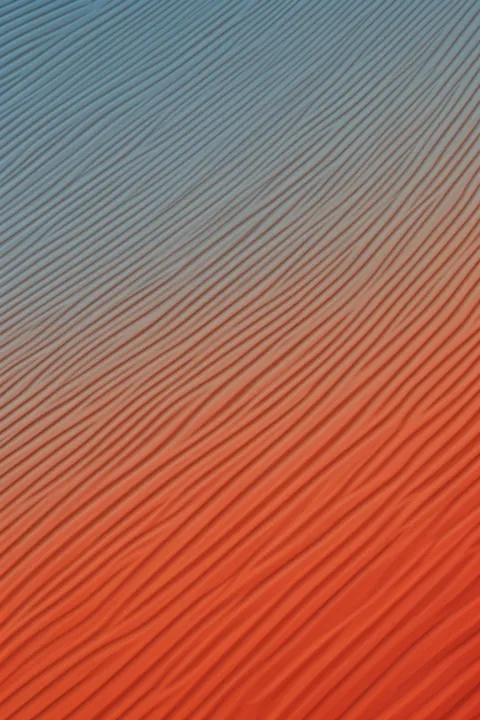 Colorful Desert Ripples. Fine diagonal ridges run across a surface that shifts from muted blue-gray to warm coral.