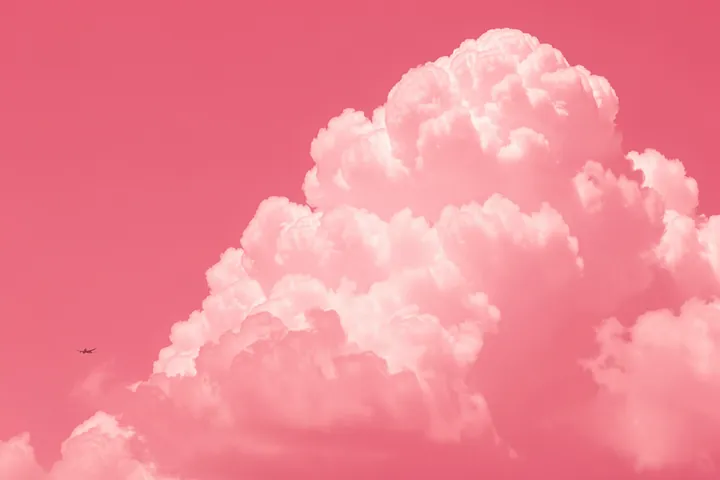 Pastel Sky Flight. A small airplane crosses a pastel pink sky filled with soft clouds.