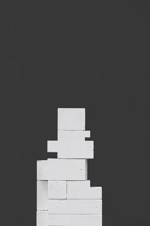 8-Bit Game Character. A small tower of white textured rectangular blocks is arranged against a charcoal-black background.