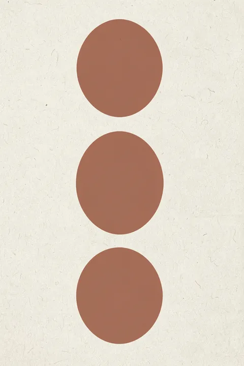 Stacked Terracotta Shapes. Three terracotta oval shapes are stacked vertically on textured off-white.
