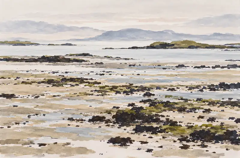 Painted low-tide shoreline with dark rocks, shallow water and distant green-topped islands under a pale sky.