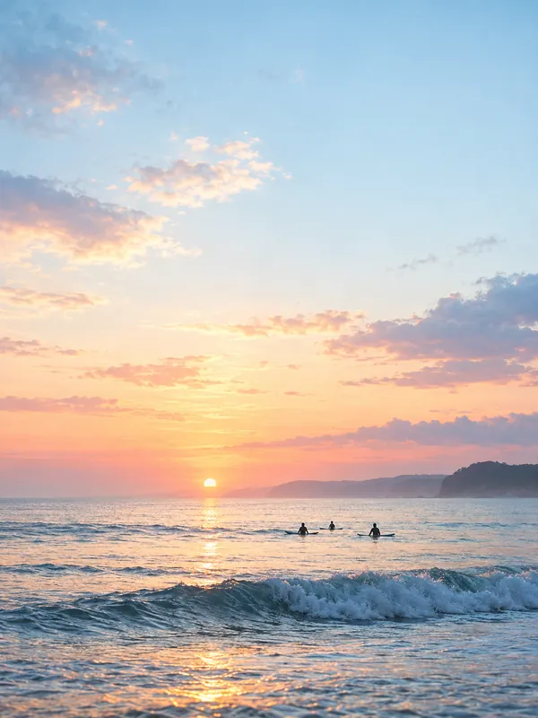 Three surfers waiting in the water at sunset, with a rolling wave and a pink-orange sky.
